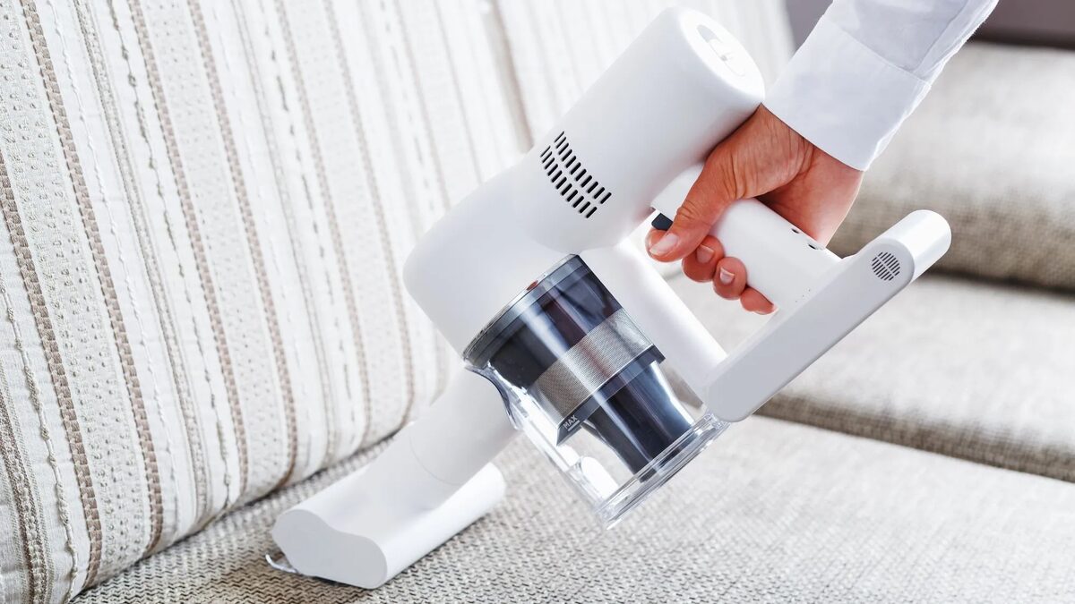 Aspirateur à main sur un canapé en tissu