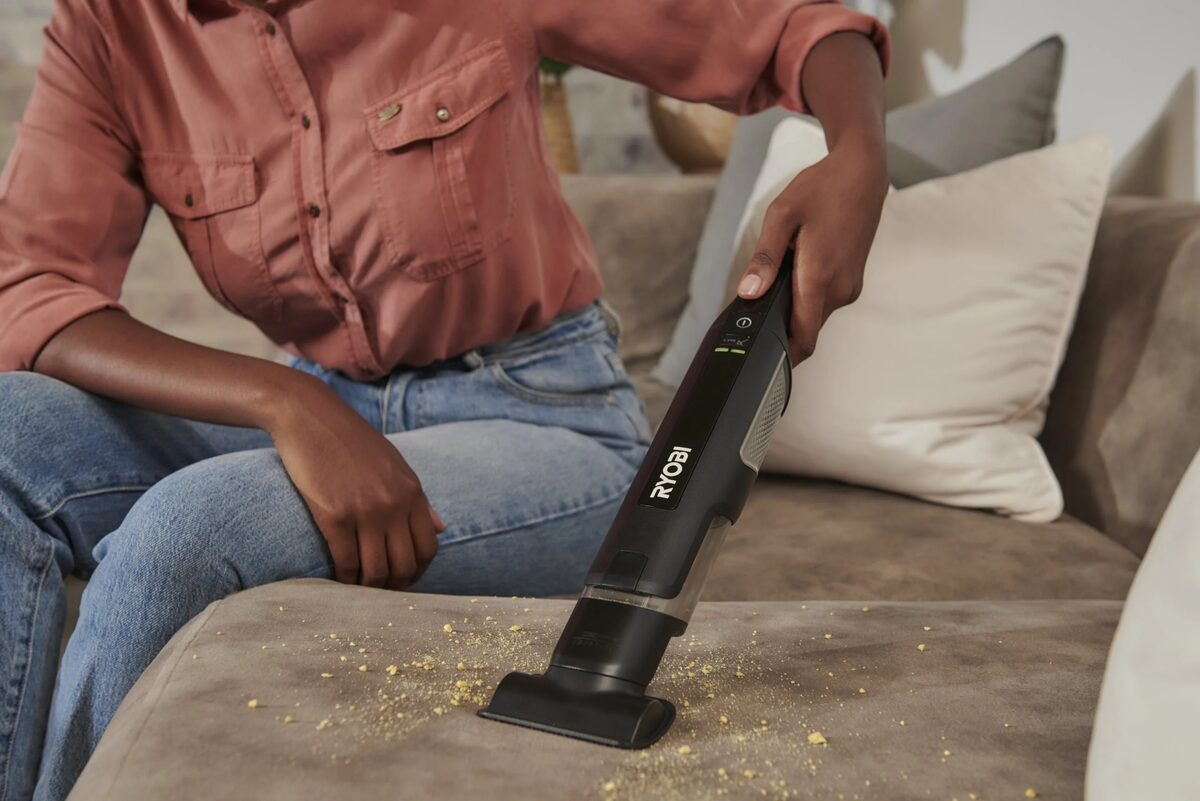 Aspirateur à main sans fil retirant des miettes sur un canapé