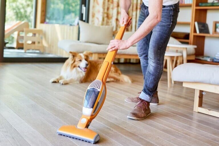 Homme passant l'aspirateur balai, chien en arrière-plan