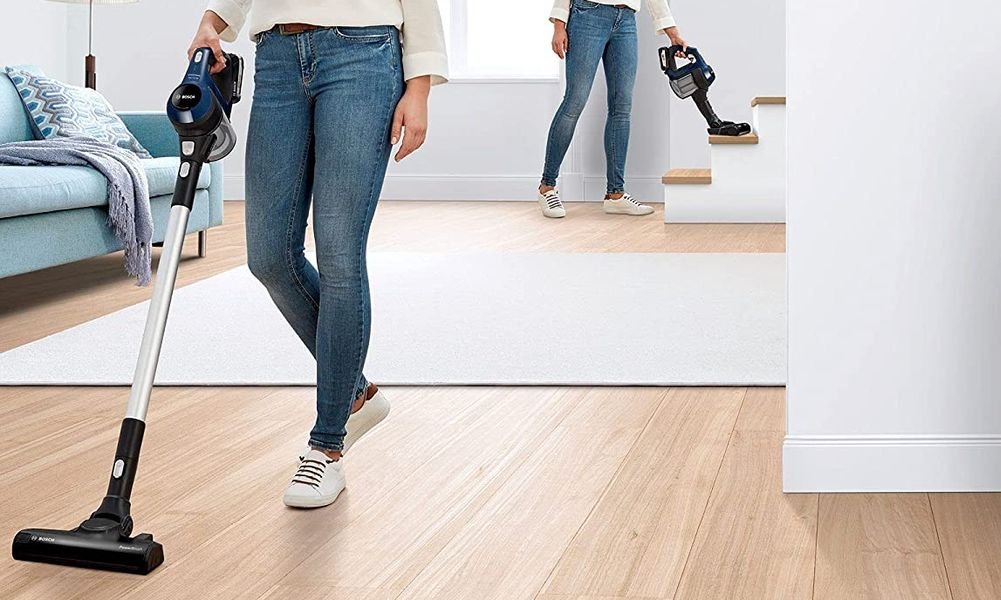 Aspirateur balai sans fil en fonctionnement sur parquet dans un salon