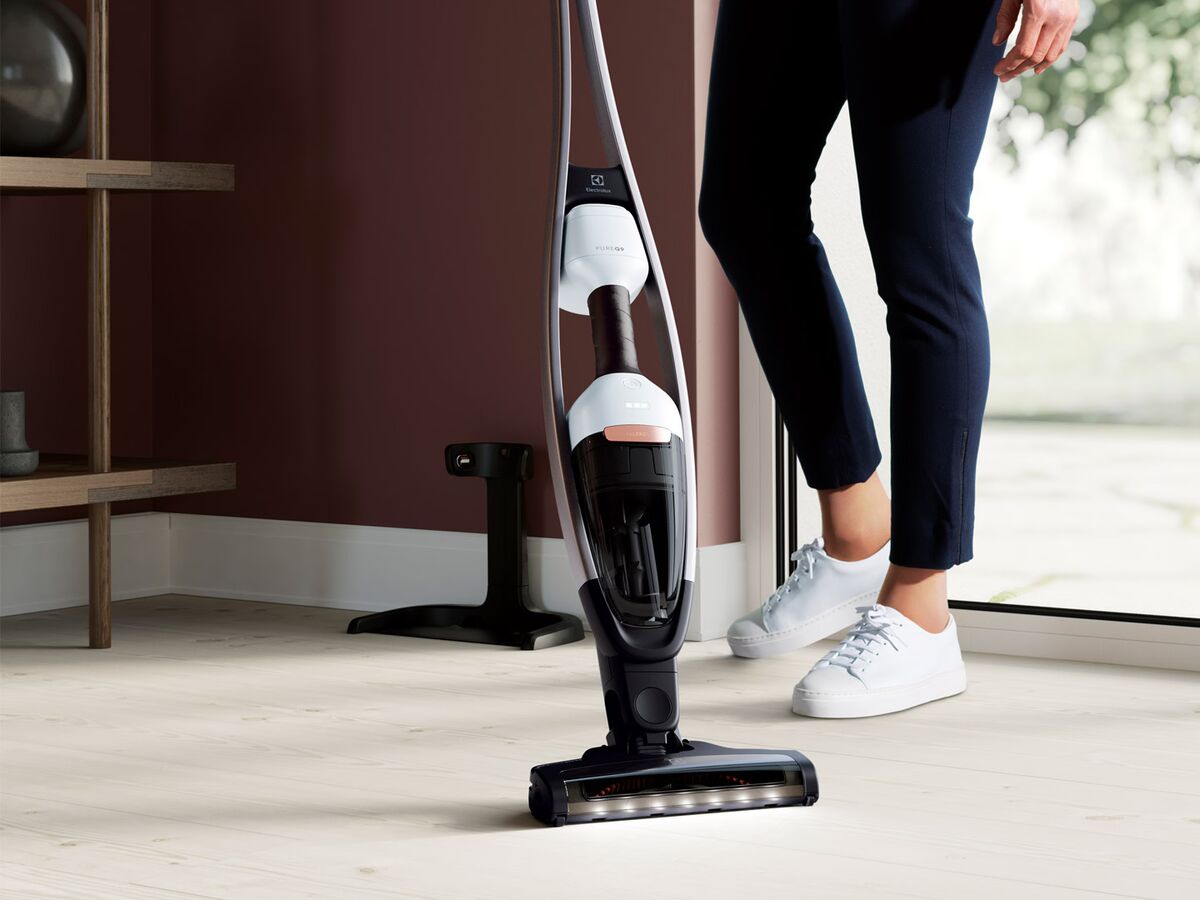 Aspirateur balai sans fil passé sur un sol clair dans un intérieur lumineux