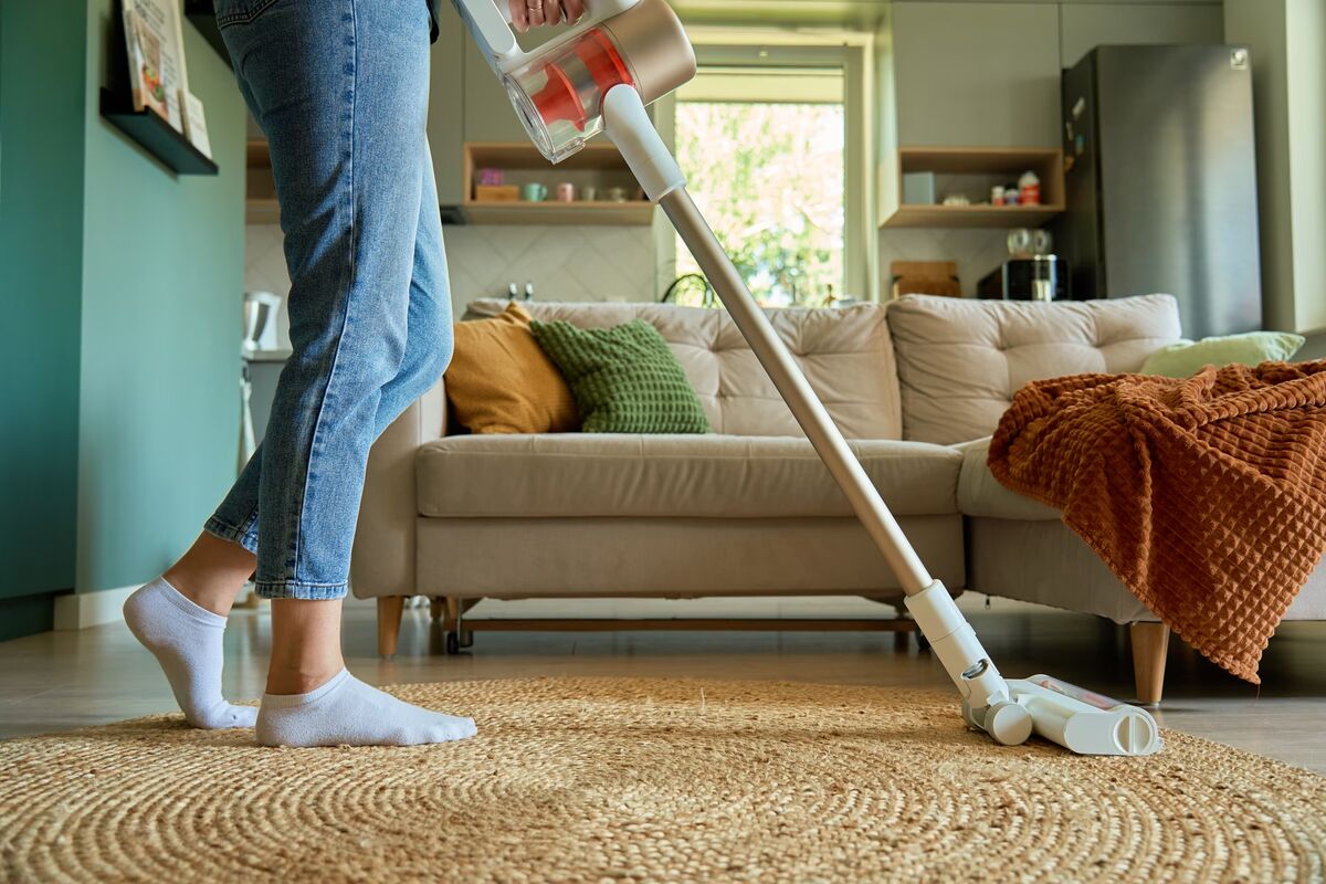 Le balai sans fil, maniable et toujours prêt Aspirateur balai sans fil passé sur un tapis en jute dans un salon