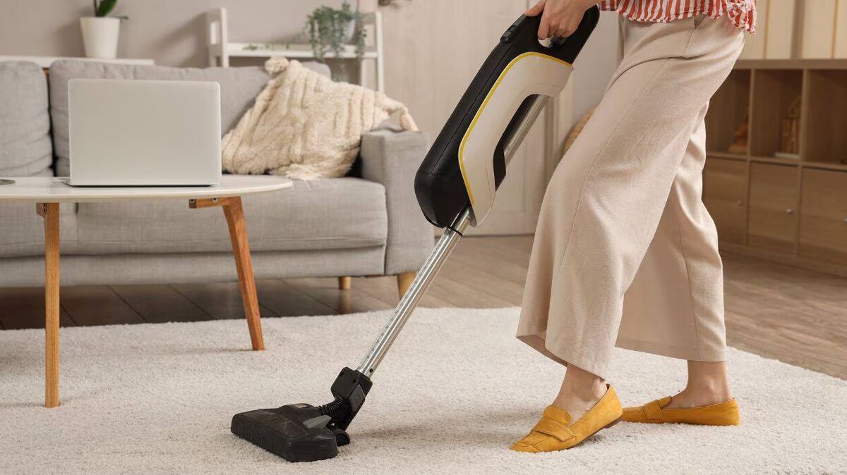 Passage de l'aspirateur balai sur un tapis dans un salon