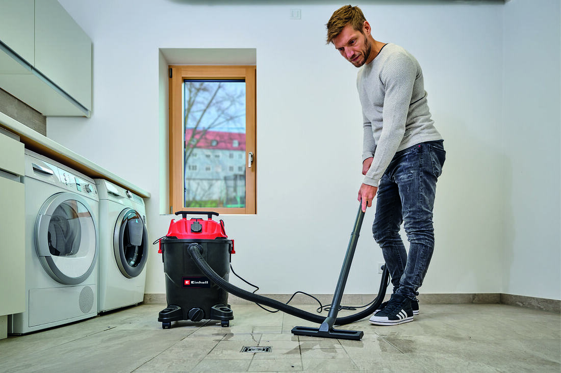 Aspirateur eau et poussière aspirant un sol mouillé dans une buanderie
